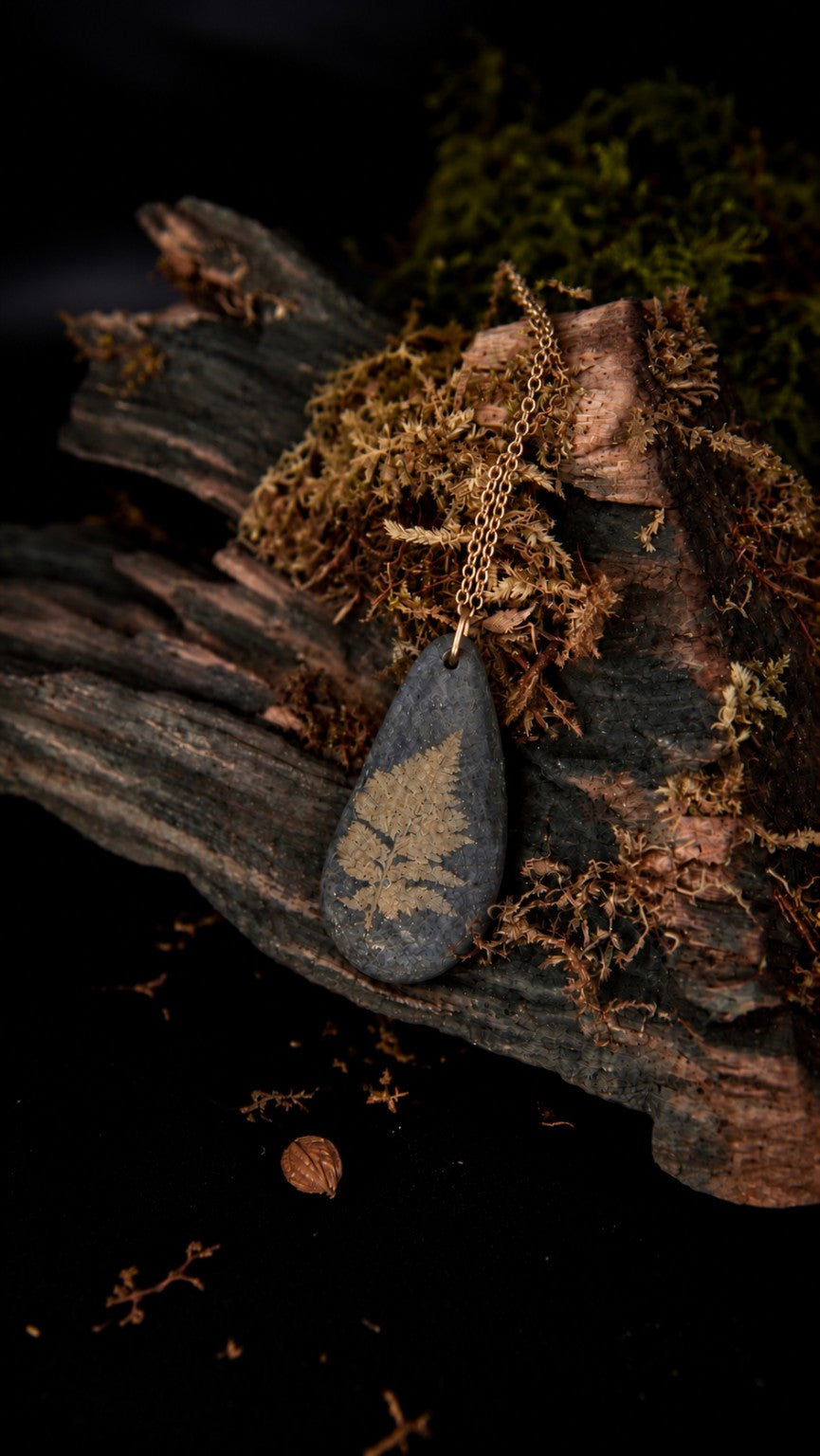 Filicea, collier Olibria en galet noir breton gravé d’une fougère, sur chaîne en acier inoxydable doré.